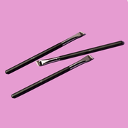 Luscious Cosmetics angled eyeliner brushes displayed on a pink background.