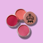 Luscious Cosmetics Blush Crush Trio featuring three pink-shade makeup products on a purple background.