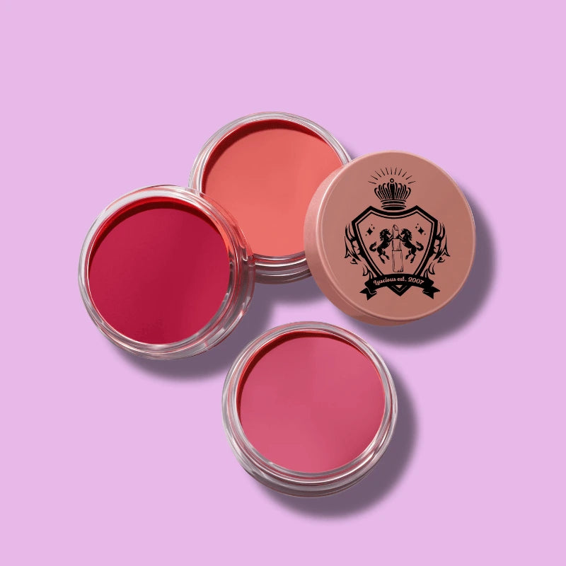 Luscious Cosmetics Blush Crush Trio featuring three pink-shade makeup products on a purple background.