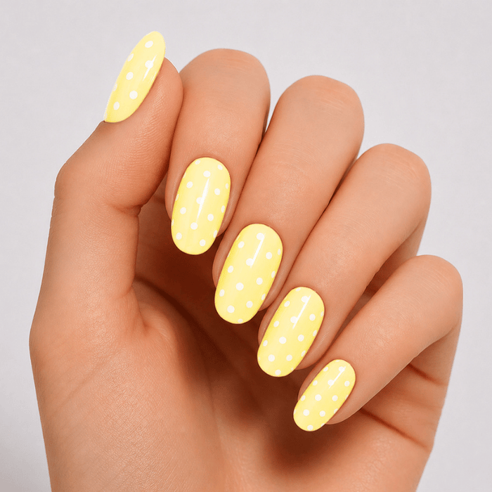 Hand wearing Luscious Cosmetics Butter Yellow short press-on nails in a glossy pastel yellow finish.