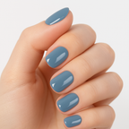 Close-up of a hand wearing Luscious Cosmetics press-on nails in a solid glossy blue color.