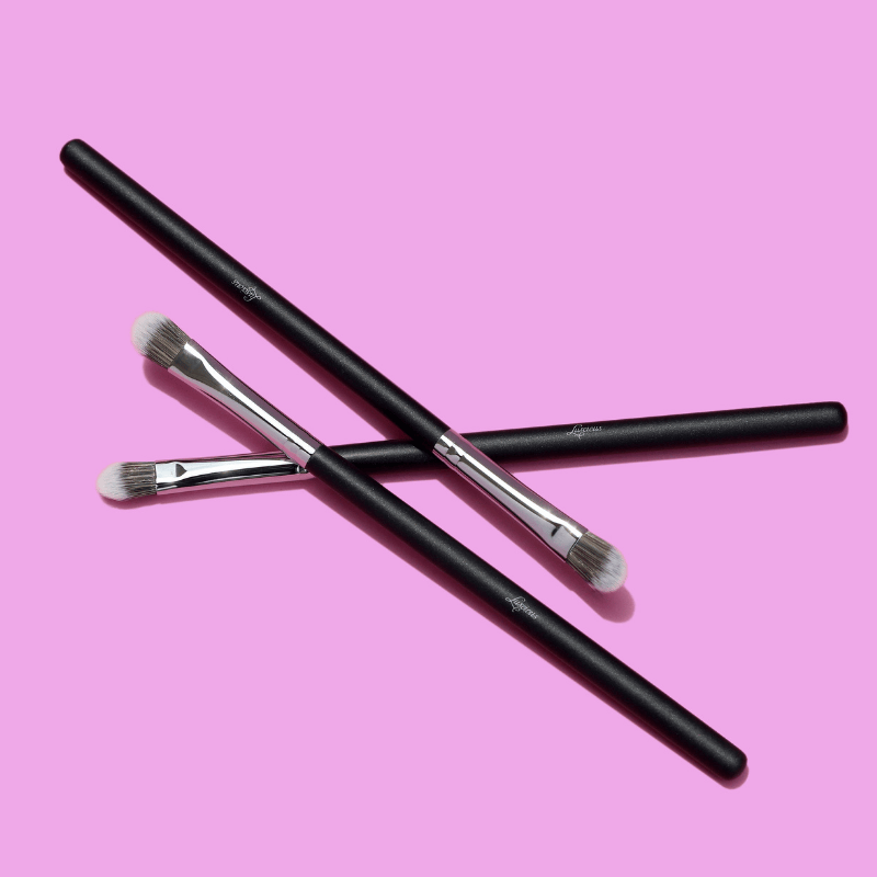 Luscious Cosmetics makeup brushes displayed on a pink background.