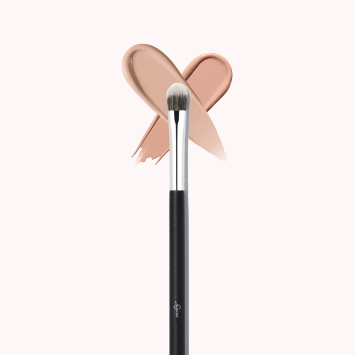 Luscious Cosmetics makeup brush with a pink bow detail and beige color swatch on a white background.