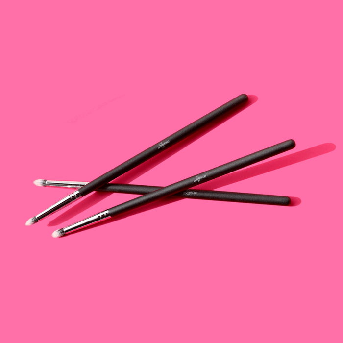 Luscious Cosmetics detailed blending brushes displayed on a pink background.
