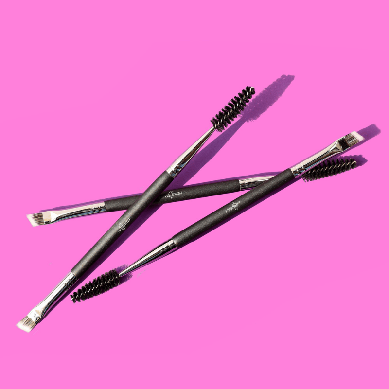 Luscious Cosmetics makeup brushes displayed on a pink background.