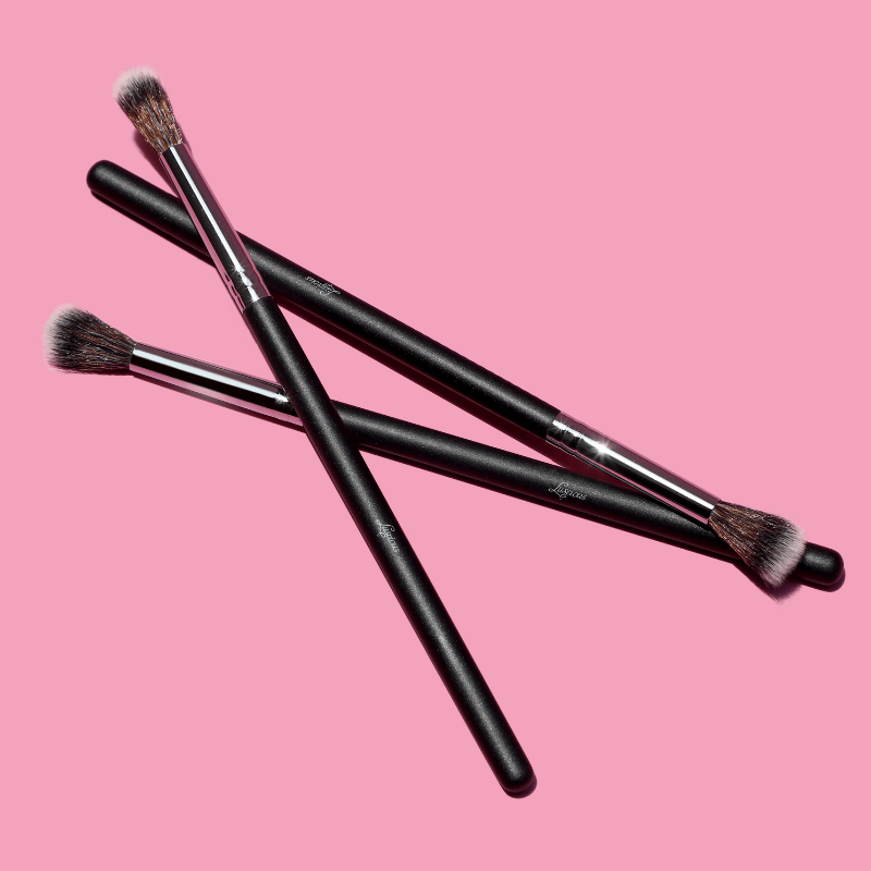 Luscious Cosmetics eyeshadow blender brushes displayed on a pink background.