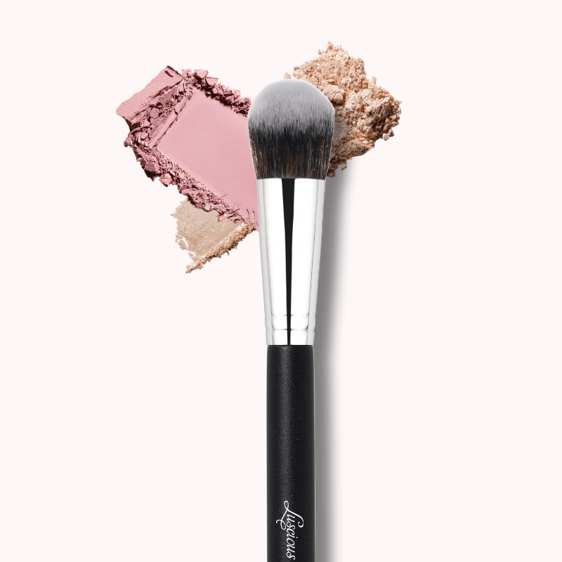 Luscious Cosmetics precision powder brush with pink and beige powder on a white background.