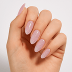 A hand wearing glossy pink glittery press-on nails by Luscious Cosmetics.