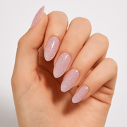 A hand wearing glossy pink glittery press-on nails by Luscious Cosmetics.