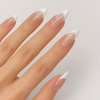 A close-up image of a hand wearing press-on nails by Luscious Cosmetics, featuring a glossy salon-quality finish with a white French tip design.