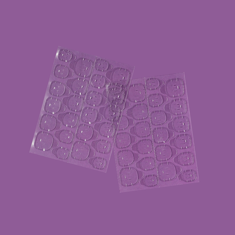 Two sheets of clear adhesive tabs by Luscious Cosmetics on a purple background.