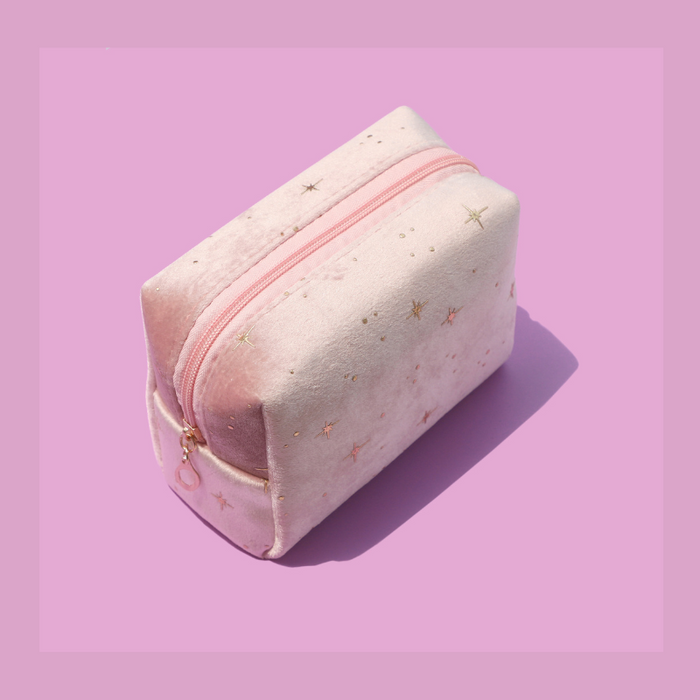 Small rectangular cosmetic pouch with a pink zipper by Luscious Cosmetics on a light pink background.